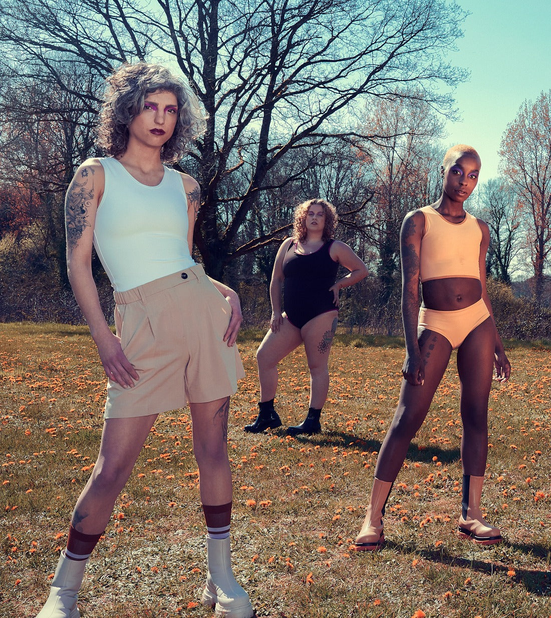 Three people standing together outdoors in an autumn field, wearing comfort apparel
